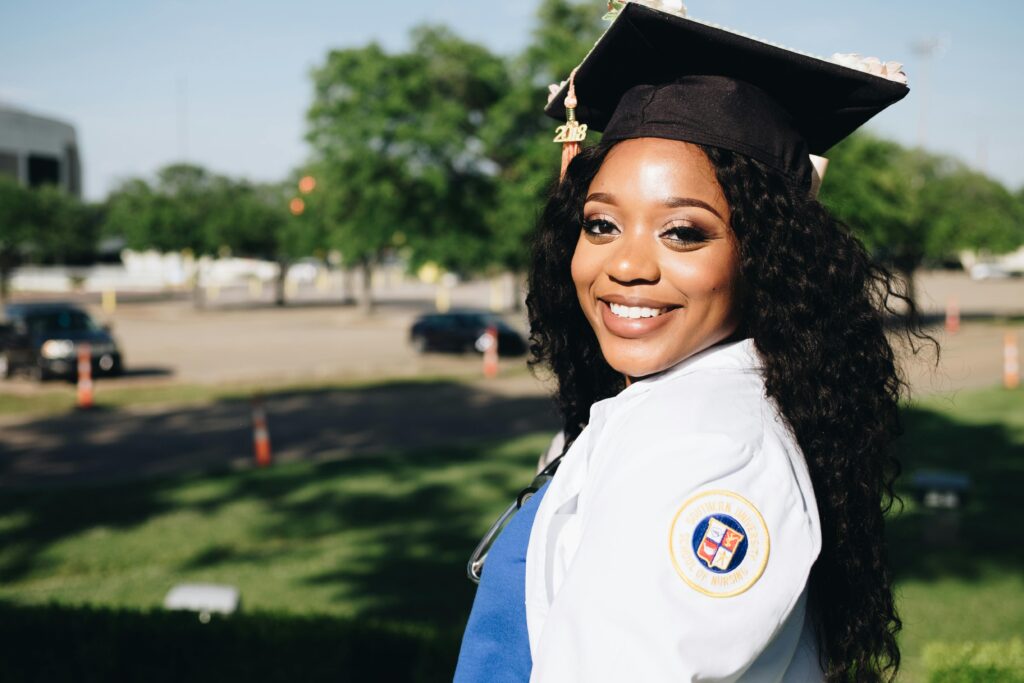 pexels-photo-1139319-1139319 African American woman in graduation attire, smiling outdoors, symbolizing academic success.
