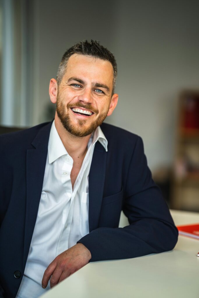 pexels-photo-12437056-12437056 Business professional in suit smiling confidently in a modern office environment.