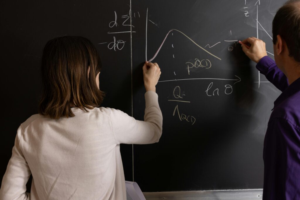 pexels-photo-28608146-28608146 Teachers collaborating on mathematical equations and graphs on a chalkboard in an educational setting.