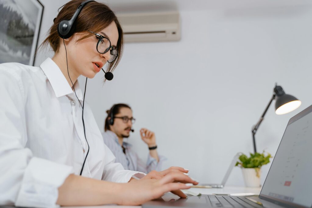 pexels-photo-7709089-7709089 Focused customer support professionals working in a modern office with headsets and laptops.