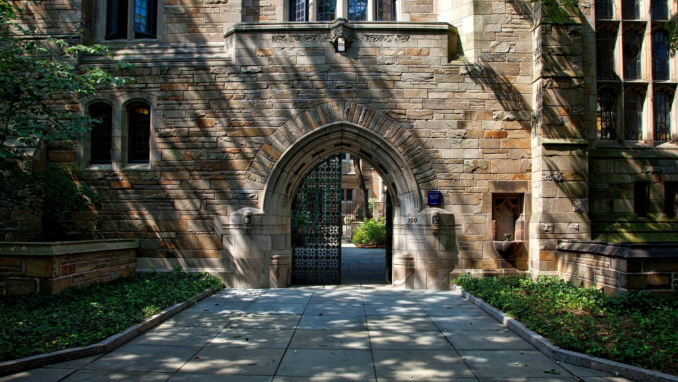 Gothic-style stone archway entrance at Yale University campus, surrounded by greenery.